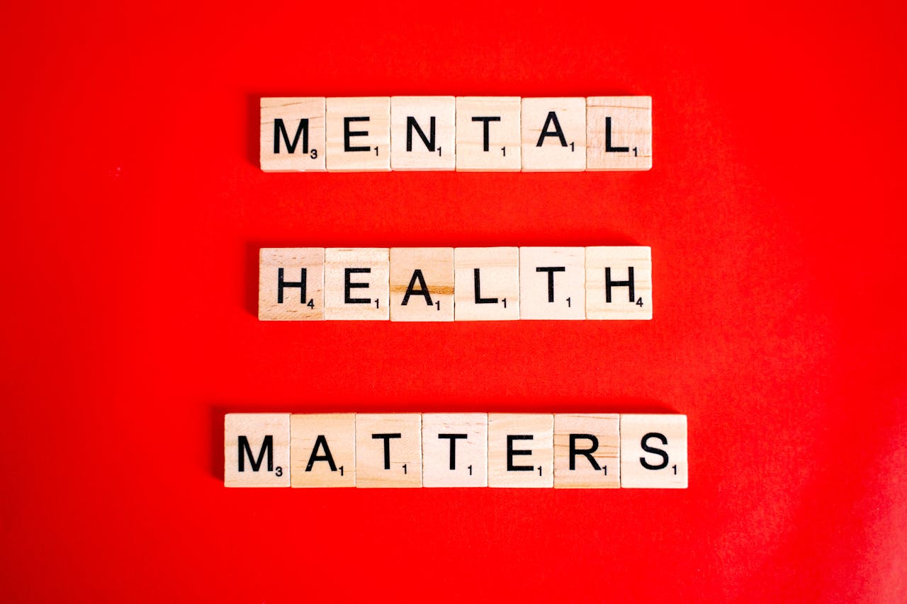 hero-img-01 Wooden tiles spelling 'Mental Health Matters' on a vivid red background.