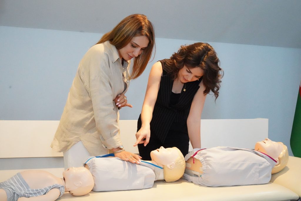 Courses Two women demonstrate CPR techniques on mannequins during a training session indoors.